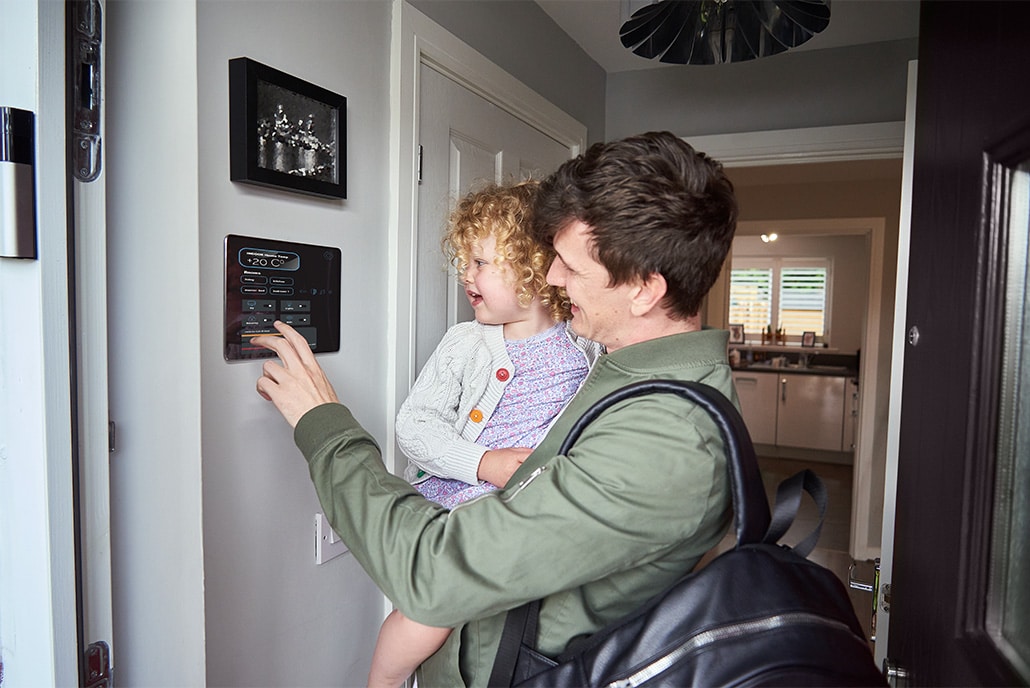 Father and infant daughter looking at a smart meter in their home